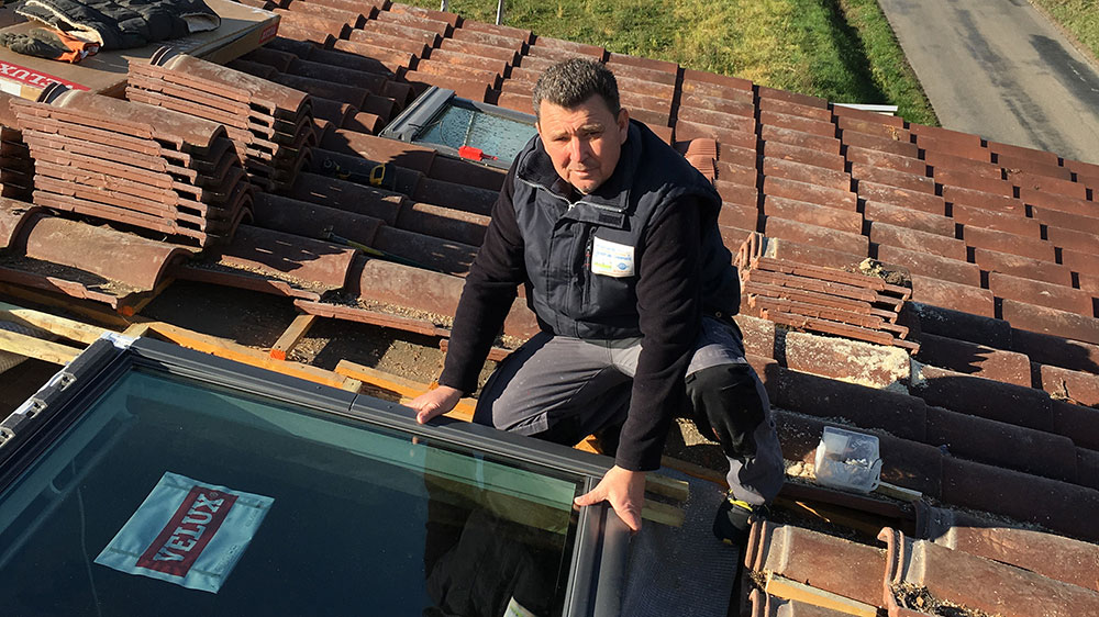 Pose d'une fenêtre de toit Velux sur une toiture en tuiles rouges