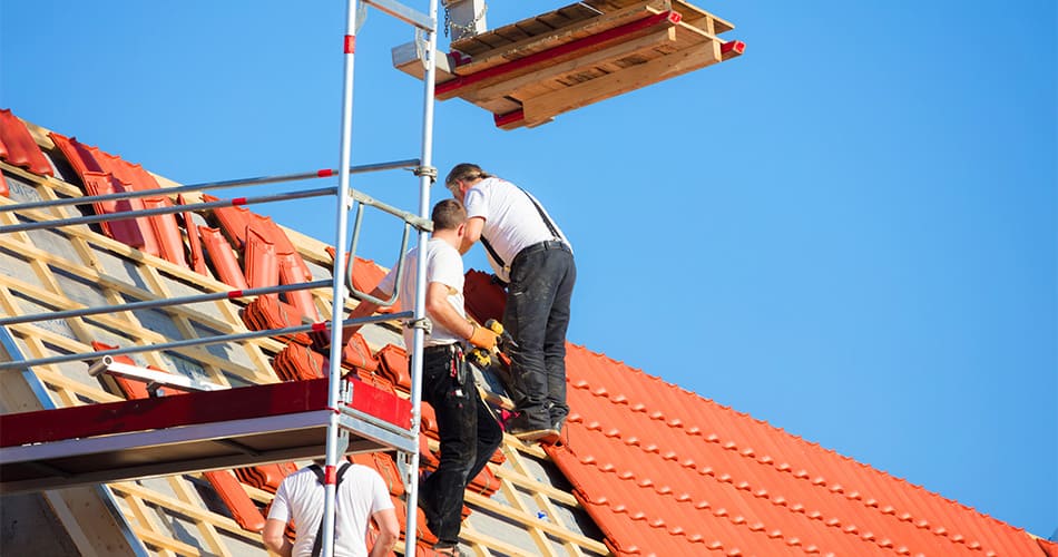 Echafaudage monté à flanc d'une maison pour poser des tuiles sur une toiture à forte pente